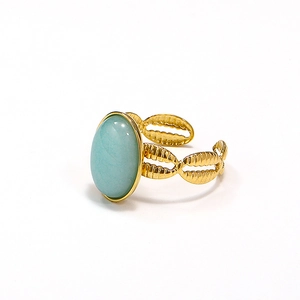 Detailed close-up of woven gold band with large oval sky blue stone on ring