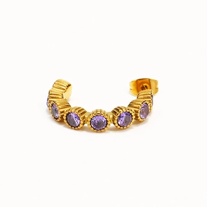 Détail de boucles d'oreilles créoles dorées ornées de zircons violets élégants