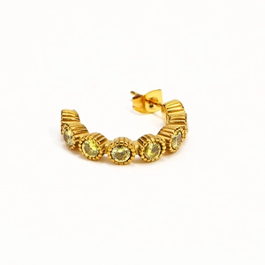 Détail d'une boucle d'oreille dorée en C avec texture verticale et cinq zircons jaunes