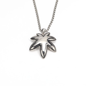 Macro shot of maple leaf pendant in polished stainless steel on a woven metal chain