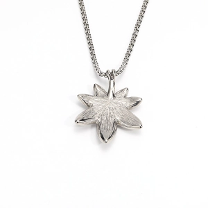 Detailed macro view of the silver maple leaf pendant with fine texture and chain