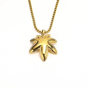 Macro shot of gold maple leaf pendant with polished metallic finish on a box chain