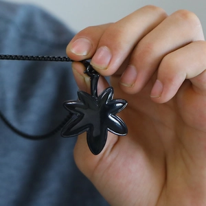 Macro shot of minimalist black maple leaf pendant with smooth glossy finish on a chain