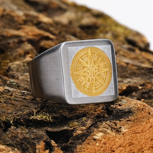 Macro detail of brushed stainless steel signet ring with golden compass and Latin engraving