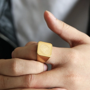 Detail of vintage matte gold signet ring with compass engraving worn on finger