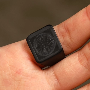 Macro shot of men's matte black stainless steel signet ring with engraved compass star