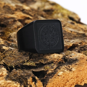 Macro shot of men's matte black stainless steel signet ring with compass engraving