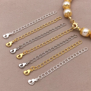 Detail view of 18K gold and silver heart-shaped extension chains on textured fabric