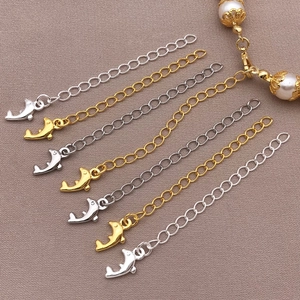 Detail of gold and silver dolphin extension chains for jewelry on brown textured fabric