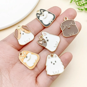 Macro shot of 6 assorted cartoon dog enamel charms on a hand for scale and DIY detail