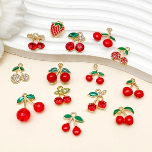 Vue détaillée de breloques fruits dorées en émail rouge pour la création de bijoux