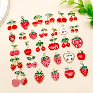 Flat lay of colorful fruit alloy charms for DIY jewelry making including strawberry and cherry