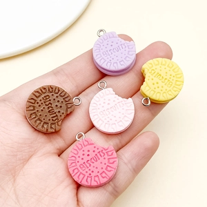 Macro view of colorful resin cookie charms with bite marks and metal rings in hand