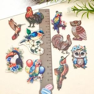 Détail de pendentifs oiseaux en acrylique imprimé avec couleurs vives et bords découpés