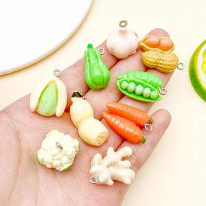 Detalle de varios dijes de vegetales en miniatura de resina con aros para creación de joyas