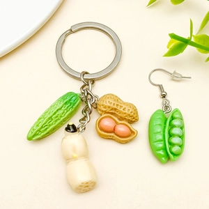 Detalle de dijes de resina de vegetales con colgantes de maíz y cacahuetes para manualidades