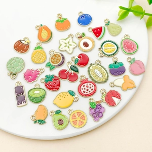 Vue macro de breloques en émail fruits sur plateau en céramique pour bijoux DIY