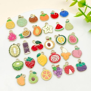 Détail de divers pendentifs en émail de fruits avec bordure dorée sur support blanc