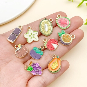 Vue macro de divers pendentifs en émail de fruits tropicaux montrant leur taille réelle