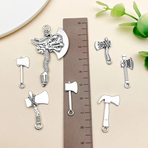 Macro detail of various antique silver axe pendants for DIY jewelry with size ruler