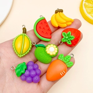 Dettaglio macro di ciondoli in resina a forma di frutta mista con anelli di metallo argento