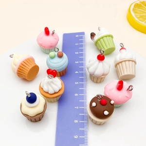 Vista dettagliata di mini ciondoli cupcake in resina con scala graduata su piatto bianco