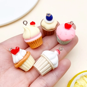 Dettaglio di cinque mini ciondoli cupcake in resina in mano per gioielli fai-da-te