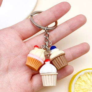 Dettaglio di tre ciondoli per cupcake in resina su un portachiavi in argento a mano