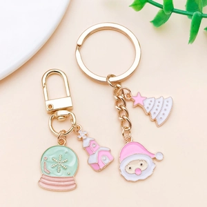 Close-up of pink Christmas charms featuring Santa and trees on gold metal keychains