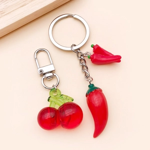 Detail of red cherry and chili resin keychains with realistic green leaves and silver hooks