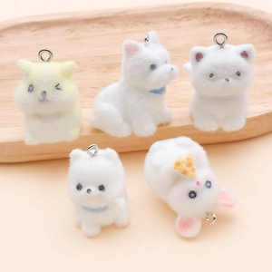 Detailed view of five cute flocked animal plush pendants with metal rings on a wooden tray