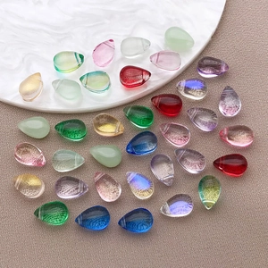 Perline di vetro colorate a forma di goccia per gioielli fai-da-te su un piatto bianco