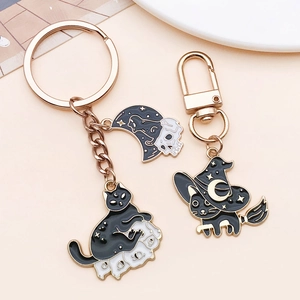 Detail van Halloween zwarte kat hangers met emaille maan en skelet motieven op roze basis