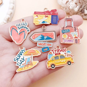 Macro shot of colorful travel-themed alloy charms on a hand showing detail and size