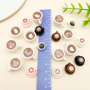 Macro detail of miniature resin coffee cup charms with heart latte art and a ruler