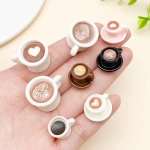 Detailed macro view of miniature coffee cups with latte art held in hand for DIY crafts