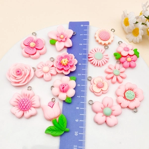 Detailed close-up of pink resin flower pendants on tray with a ruler for size reference