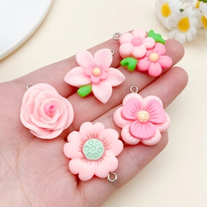 Close-up of pink resin flower charms with metal loops for DIY jewelry making held in palm