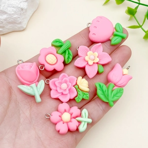 Detailansicht von rosa Blumenanhängern aus Harz in der Hand für DIY-Schmuckherstellung