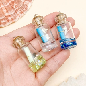 Close-up of three mini resin driftwood bottle pendants with shells and scrolls