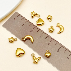 Macro shot of 18k gold plated DIY charms including heart and star shapes with ruler measurement