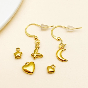 Macro shot of 7-piece DIY gold jewelry charms including heart, moon, and star pendants