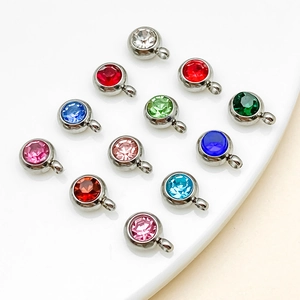 Gros plan de 12 pendentifs en cristal coloré avec montures en acier inoxydable poli argent