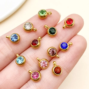Detalle de colgantes de piedra natal en acero dorado 6mm con circones redondos