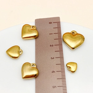 Detailed size comparison of golden heart pendants from 12mm to 22mm on a ruler