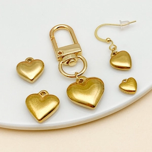 Golden heart-shaped jewelry pendants and DIY earring components on white display