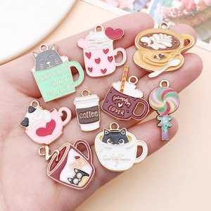 Detailed view of assorted enamel cat coffee cup charms held in a hand for jewelry making