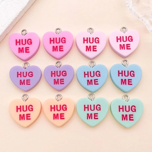 Close-up of 12 colorful resin heart charms with red Hug Me text and silver loops