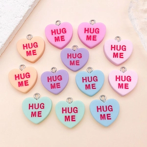 Macro detail of resin heart charms with Hug Me text and silver metal jump rings