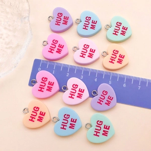 Macro shot showing 20mm colorful resin heart charms with Hug Me text and sizing ruler